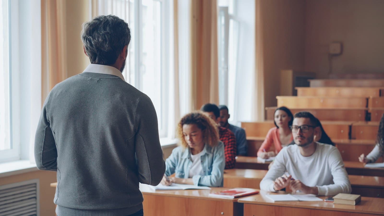 A teacher speaking to students in a lecture hall